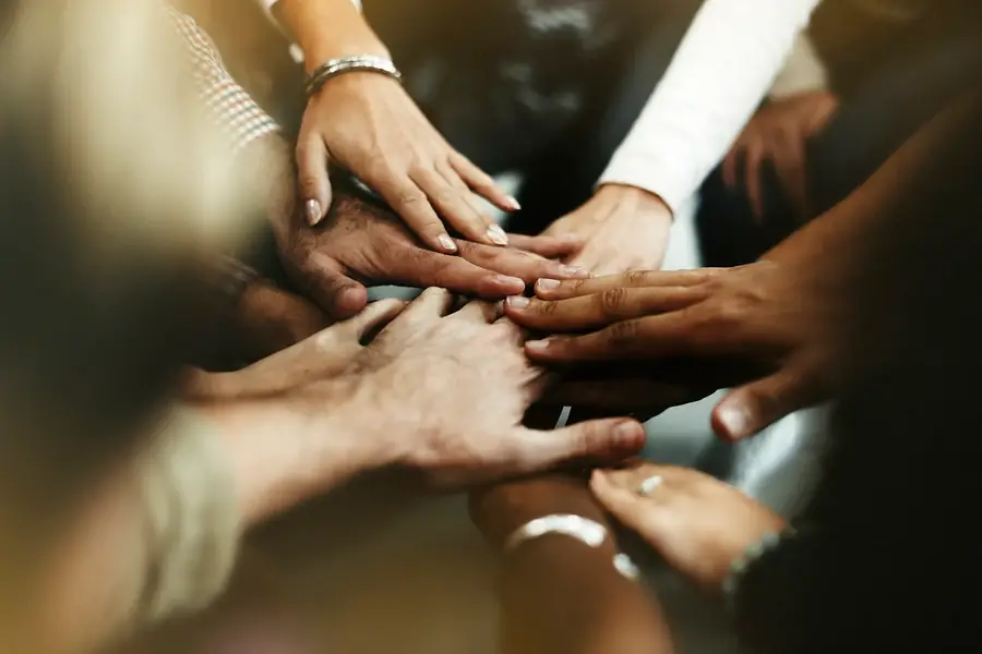 Close de várias mãos de pessoas diferentes sobrepostas umas às outras
