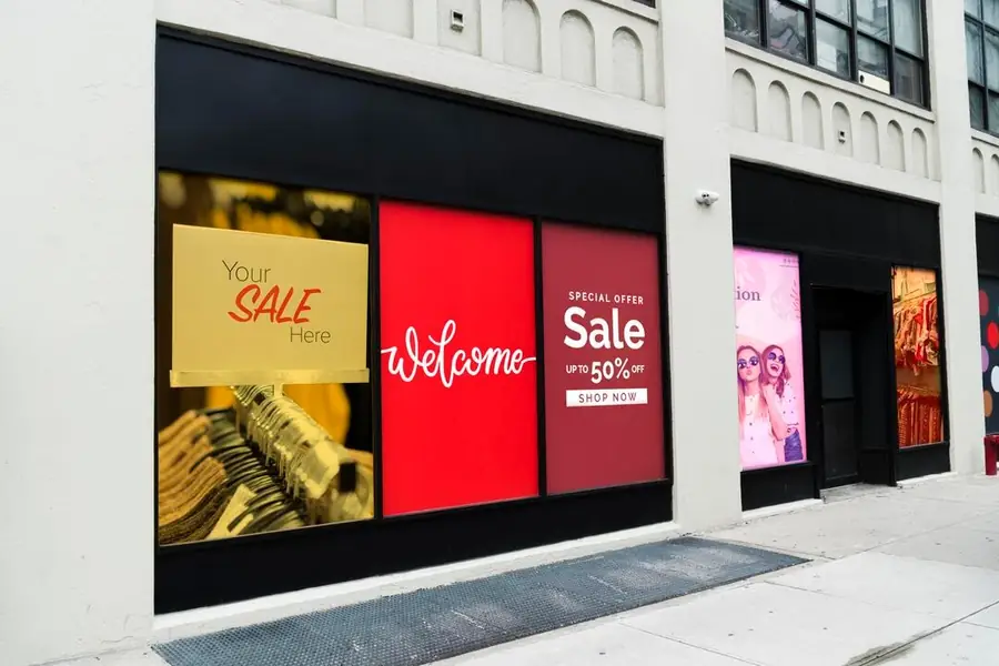 Fachada de loja com três painéis digitais lado a lado exibindo "Your sale here", "Welcome" e uma oferta de 50%